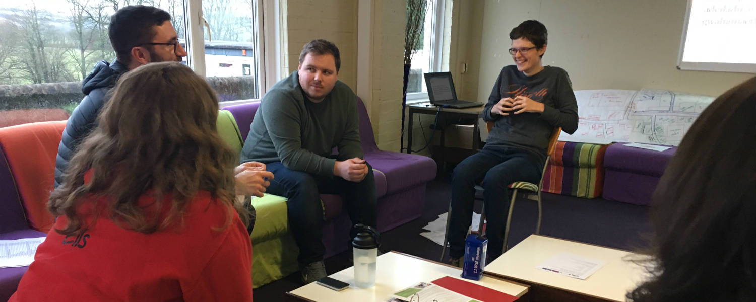 5 people around a coffee table having a meeting 