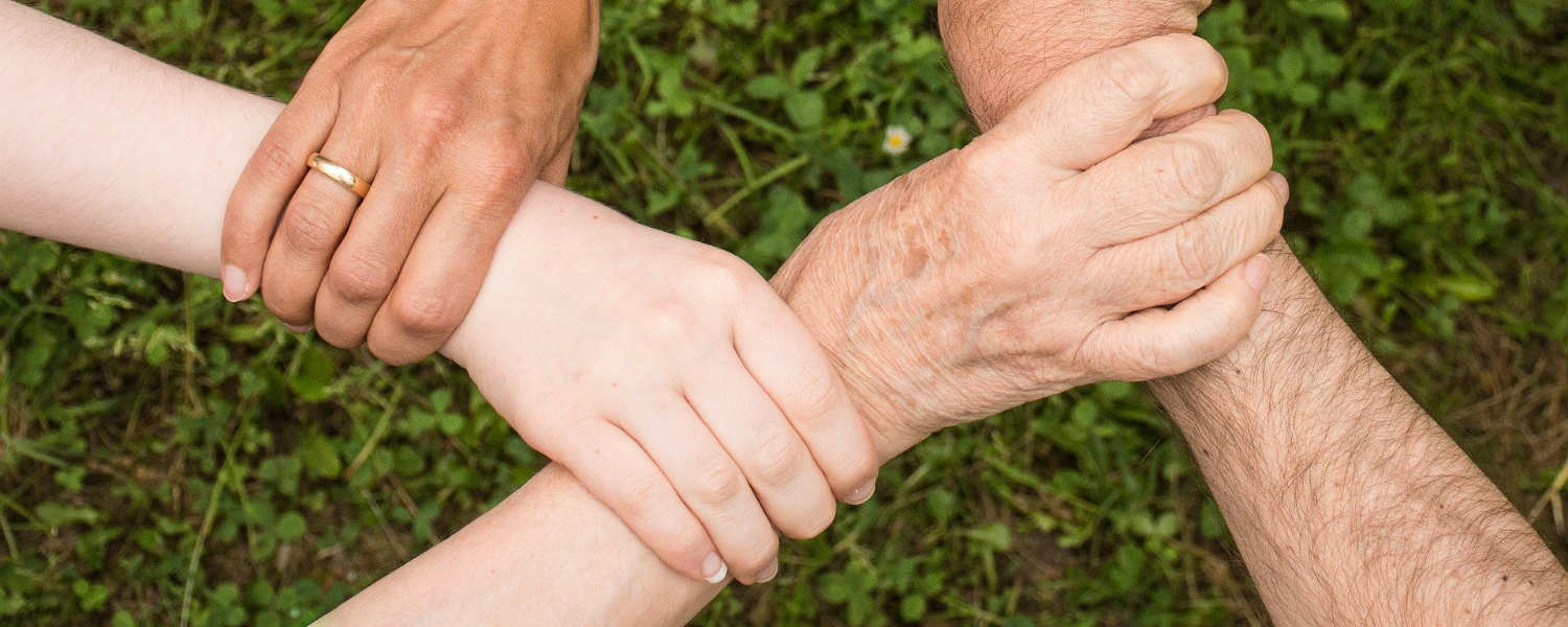4 different aged people linking hands
