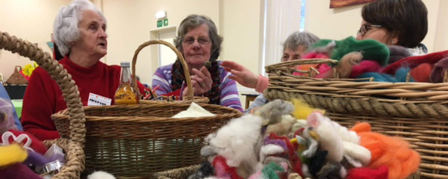 Arts and crafts on a table with 3 older ladies sat behind
