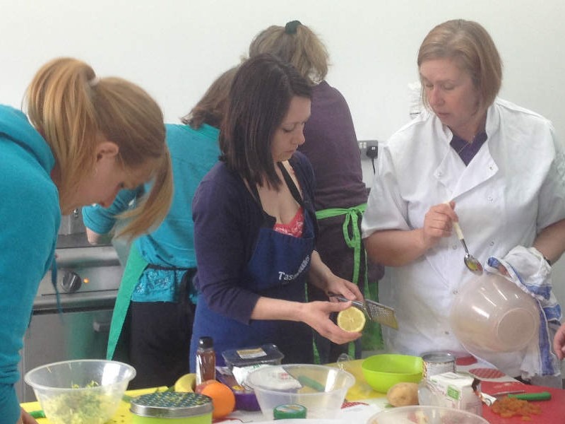 Mums preparing food in a training kitchen with Chef giving instructions